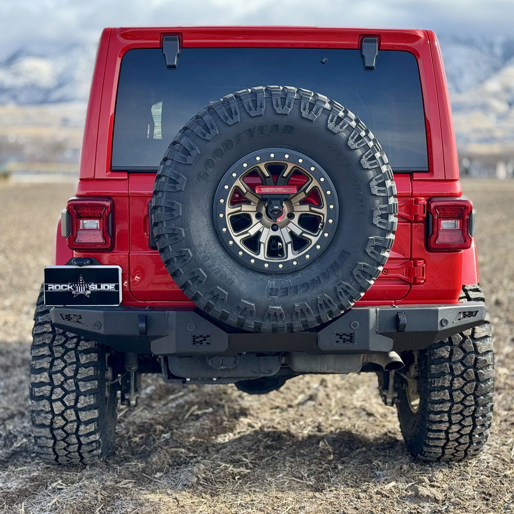 Red Jeep Wrangler with spare tire on a mountainous landscape